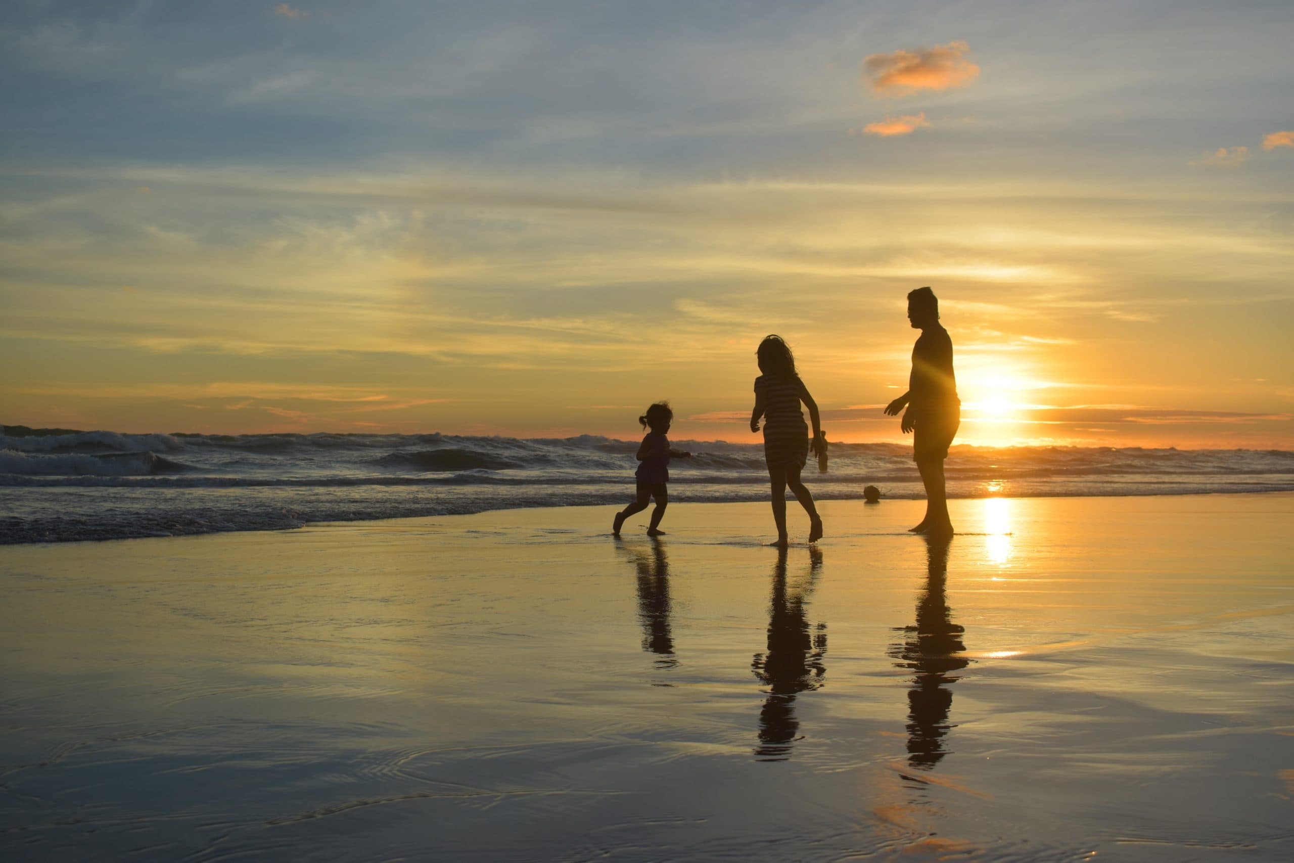 family happily playing on the beach at sunset for impute income to Mother on welfare case